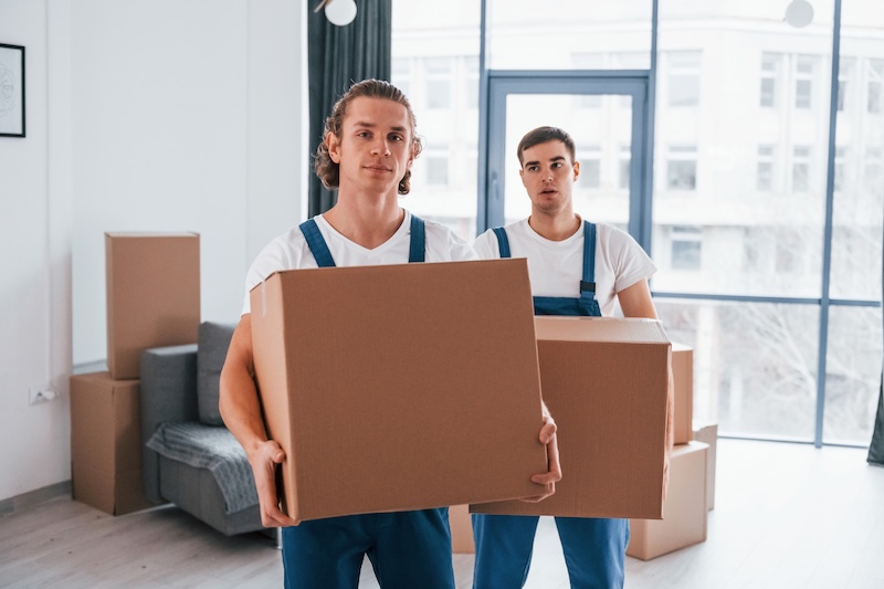 Två män från flyttfirma som bär lådor